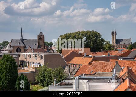 Sluis, Paesi Bassi - 5 agosto 2021: Skyline del tetto rosso con Sint Johannes de Doperkerk (Giovanni Battista) e Belfry che torreggia su di esso sotto il cl blu Foto Stock