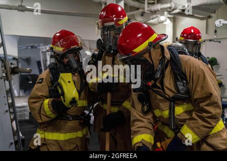 PACIFIC OCEAN (24 agosto 2021) i marinai simulano di spegnere un incendio durante una trivella per il controllo dei danni a bordo della nave di sbarco del molo anfibio USS Pearl Harbor (LSD 52), agosto 24. Pearl Harbor, parte dell'USS Essex Amphibious Ready Group (ARG), insieme all'undicesimo MEU, opera nell'area di responsabilità della settima flotta degli Stati Uniti per migliorare l'interoperabilità con alleati e partner e fungere da pronta forza di reazione per difendere la pace e la stabilità nella regione dell'Indo-Pacifico. (STATI UNITI Foto Navy di Mass Communication Specialist terza classe Sang Kim) Foto Stock