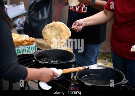 I cuochi volontari nativi americani fanno tacos indiani o pane fritto indiano in uno stand di cibo all'aperto presso l'annuale mercato indiano di Santa Fe in New Mexico. Foto Stock