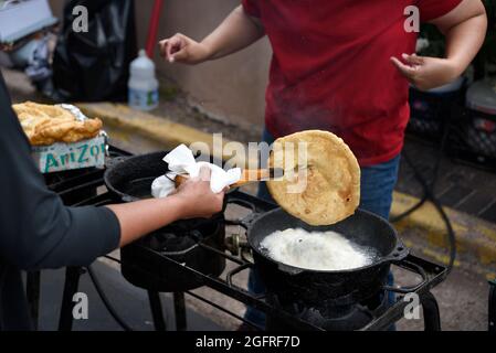 I cuochi volontari nativi americani fanno tacos indiani o pane fritto indiano in uno stand di cibo all'aperto presso l'annuale mercato indiano di Santa Fe in New Mexico. Foto Stock