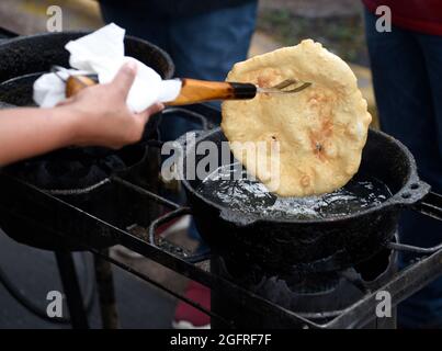 I cuochi volontari nativi americani fanno tacos indiani o pane fritto indiano in uno stand di cibo all'aperto presso l'annuale mercato indiano di Santa Fe in New Mexico. Foto Stock