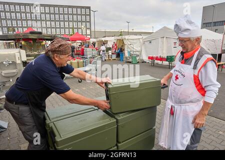 Grafschaft, Germania. 23 Agosto 2021. Gli assistenti del centro di ristorazione tedesco della Croce Rossa portano cibo in contenitori termici ai veicoli che viaggiano verso i punti di distribuzione. Qui, più di 10000 pasti sono preparati tre volte al giorno per le vittime del disastro alluvionale dell'Ahr e per i numerosi aiutanti. Credit: Thomas Frey/dpa/Alamy Live News Foto Stock