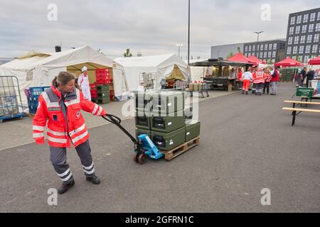 Grafschaft, Germania. 23 Agosto 2021. Un assistente del centro di ristorazione tedesco della Croce Rossa porta il cibo in contenitori termici ai veicoli che guidano verso i punti di distribuzione. Qui, più di 10000 pasti sono preparati tre volte al giorno per le vittime del disastro alluvionale dell'Ahr e per i numerosi aiutanti. Credit: Thomas Frey/dpa/Alamy Live News Foto Stock