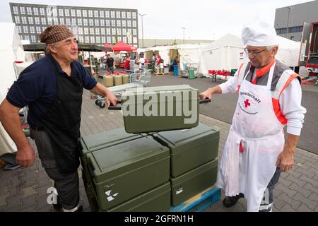 Grafschaft, Germania. 23 Agosto 2021. Gli assistenti del centro di ristorazione tedesco della Croce Rossa portano cibo in contenitori termici ai veicoli che viaggiano verso i punti di distribuzione. Qui, più di 10000 pasti sono preparati tre volte al giorno per le vittime del disastro alluvionale dell'Ahr e per i numerosi aiutanti. Credit: Thomas Frey/dpa/Alamy Live News Foto Stock