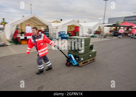 Grafschaft, Germania. 23 Agosto 2021. Un assistente del centro di ristorazione tedesco della Croce Rossa porta il cibo in contenitori termici ai veicoli che guidano verso i punti di distribuzione. Qui, più di 10000 pasti sono preparati tre volte al giorno per le vittime del disastro alluvionale dell'Ahr e per i numerosi aiutanti. Credit: Thomas Frey/dpa/Alamy Live News Foto Stock