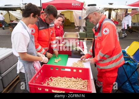 Grafschaft, Germania. 23 Agosto 2021. L'equipaggio della cucina del centro di ristorazione tedesco della Croce Rossa sta già cucinando il pranzo al mattino. Qui, più di 10000 pasti sono preparati tre volte al giorno per le vittime del disastro alluvionale dell'Ahr e per i numerosi aiutanti. Credit: Thomas Frey/dpa/Alamy Live News Foto Stock