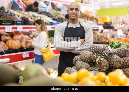 Dipendente spagnolo in negozio di frutta con ananas Foto Stock