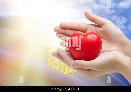 Le mani del bambino tengono un cuore sullo sfondo della bandiera di Alberta, concetto di assistenza sanitaria. Foto Stock