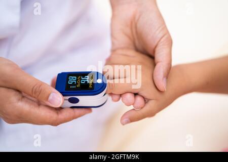 Medico controllo della pulsazione di sangue del bambino con ossimetro Foto Stock