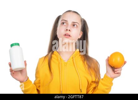 teen girl scegliere tra frutta d'arancia e pillola di vitamina in barattolo, additivi alimentari. Foto Stock