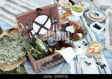 cestino da picnic pieno di vino e cibo su una coperta da picnic Foto Stock