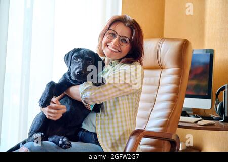 Ritratto di donna di mezza età e nero labrador cucciolo cane Foto Stock