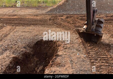 Scavatore scavare fossato di drenaggio nel sito di estrazione della torba. Drenaggio di torbiere e distruzione di alberi. Perforazione su palude per l'esplorazione petrolifera. Zona umida Foto Stock