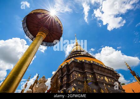 Antica pagoda dorata con ombrello di Wat Phrathat Tempio di Lampang Luang con forma di stella solare su cielo blu nuvoloso, provincia di Lampang, Thailandia. Foto Stock