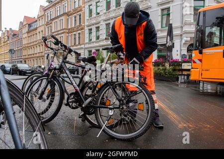 Hannover, Germania. 27 ago 2021. Timo Clever, dipendente di aha Zweckverband Abfallwirtschaft Region Hannover, apre serrature per biciclette con l'aiuto di un smerigliatrice angolare. L'azienda aha sta rimovendo ancora una volta le cosiddette "bici a schiaffo" che si trovano da mesi sugli angoli della strada e che ovviamente non vengono più utilizzate. Credit: Julian Stratenschulte/dpa/Alamy Live News Foto Stock