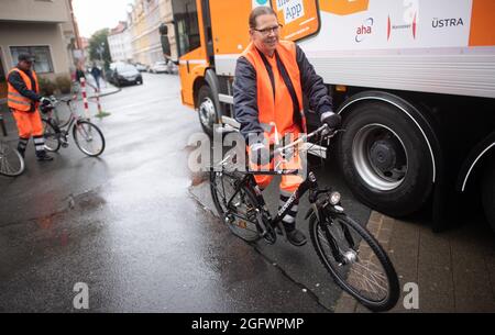 Hannover, Germania. 27 ago 2021. Angelika Clever, un dipendente dell'aha Zweckverband Abfallwirtschaft Region Hannover, porta una vecchia bicicletta in un camion dei rifiuti. L'azienda aha sta rimovendo ancora una volta le cosiddette "bici a schiaffo" che si trovano da mesi sugli angoli della strada e che ovviamente non vengono più utilizzate. Credit: Julian Stratenschulte/dpa/Alamy Live News Foto Stock