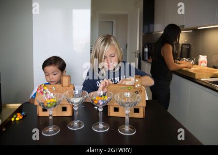 Fratelli che decorano case di pan di zenzero Foto Stock