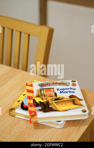 POZNAN, POLONIA - 03 dicembre 2015: Una foto verticale di due piccoli libri per bambini sui veicoli da costruzione in polacco su un tavolo di legno. Foto Stock