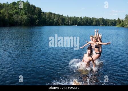 Giovani amici che saltano nel lago Foto Stock