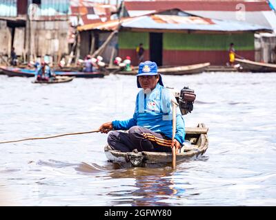 Belen, Perù - Dic 2019: Uomo che pesca dalla piccola barca di legno tra le case nella pianura alluvionale del fiume Itaya, la parte più povera di Iquitos - Belén. V Foto Stock