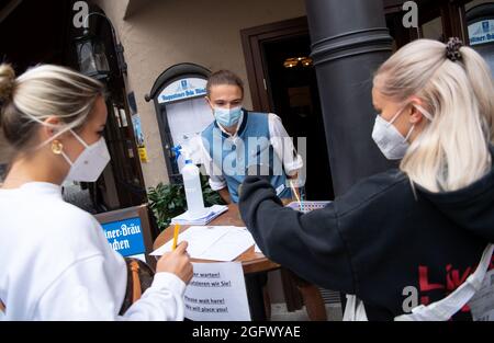 27 agosto 2021, Baviera, Monaco: Un dipendente di un pub controlla la prova 3G di due ospiti all'ingresso. Gli ospiti del ristorante devono essere vaccinati, sottoposti a test o recuperati quando soggiornano all'interno. Foto: Sven Hoppe/dpa Foto Stock