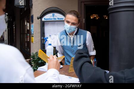 27 agosto 2021, Baviera, Monaco: Un dipendente di un pub controlla la prova 3G di due ospiti all'ingresso. Gli ospiti del ristorante devono essere vaccinati, sottoposti a test o recuperati quando soggiornano all'interno. Foto: Sven Hoppe/dpa Foto Stock