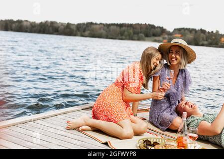 Amici donne che hanno pic-nic sul molo Foto Stock