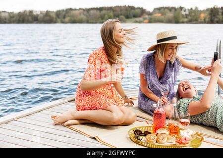 Amici donne che hanno pic-nic sul molo Foto Stock