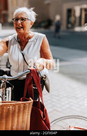 Donna anziana in piedi vicino alla bicicletta Foto Stock
