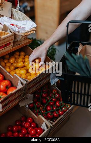 Uomo in negozio che sceglie i pomodori Foto Stock