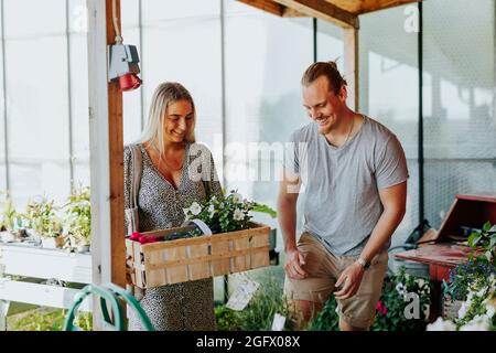 Coppia sorridente che sceglie i fiori in negozio Foto Stock