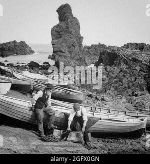 Una vista dei pescatori dell'inizio del XX secolo che si preparano per una giornata di pesca sulla spiaggia vicino al Selciato del gigante nella contea di Antrim, Irlanda del Nord. Foto Stock