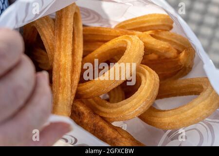 Primo piano di churros spagnoli fritti avvolti in un foglio di carta Foto Stock