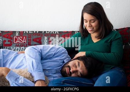Ragazzo ispanico che dorme su un allegro grembo di Latina sul divano Foto Stock