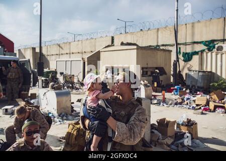 Una Marina assegnata a Special Purpose Marine Air-Ground Task Force-Crisis Response-Central Command tiene un bambino mentre sua madre è ricercata all'Aeroporto Internazionale Hamid Karzai, 23 agosto. I membri del servizio degli Stati Uniti stanno assistendo il Dipartimento di Stato con un'operazione DI evacuazione non combatante (NEO) in Afghanistan. (STATI UNITI Foto del corpo marino di 1° Ora. Mark Andries) Foto Stock