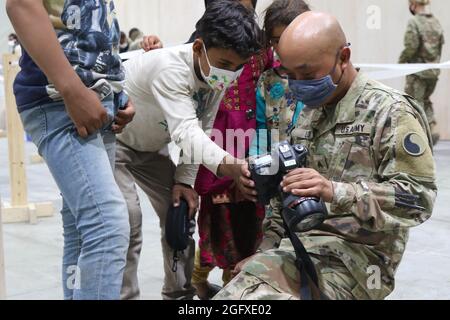 Un soldato della Guardia Nazionale degli Stati Uniti con Task Force Spartan, il Centro militare degli Stati Uniti condivide le foto scattate con gli sfollati afghani durante il processo di arrivo a Camp Buehring, Kuwait, 25 agosto 2021. I soldati USARCENT di tutte le componenti stanno sostenendo gli sforzi di evacuazione dell'Afghanistan in una varietà di modi per includere la cattura di foto dei molti momenti di cura e compassione. (STATI UNITI Esercito foto di PFC. Katelynn Bissell) Foto Stock