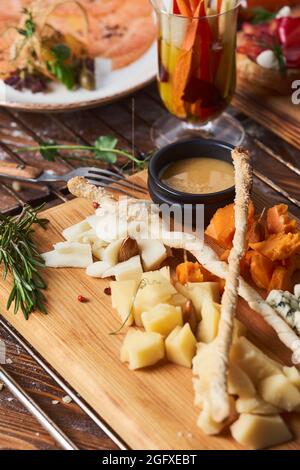 antipasti, diversi tipi di formaggio su un asse di legno con miele Foto Stock