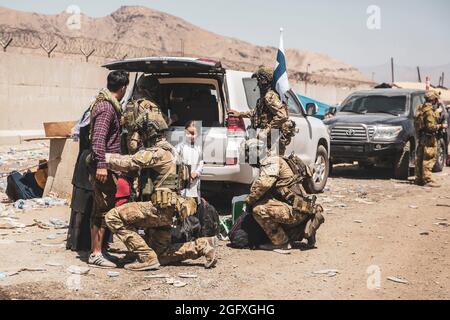 Le forze della coalizione finlandese assistono gli sfollati per il trattamento successivo durante un'evacuazione all'aeroporto internazionale Hamid Karzai, Kabul, Afghanistan, 24 agosto. I membri del servizio degli Stati Uniti e le forze di coalizione stanno assistendo il Dipartimento di Stato con un'operazione di evacuazione non combattente (NEO) in Afghanistan. (STATI UNITI Foto del corpo marino di staff Sgt. Victor Mancilla) Foto Stock