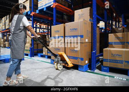 (210827) -- ZHENGZHOU, 27 agosto 2021 (Xinhua) -- un membro del personale prepara la spedizione di tute protettive mediche per l'aria condizionata in un magazzino del gruppo Tuoren nella città di Changyuan di Xinxiang, provincia centrale di Henan della Cina, 26 agosto 2021. Il produttore cinese di consumabili medici Tuoren Group ha sviluppato un tuta protettiva medica a pressione positiva per l'aria condizionata che può fornire aria fredda agli operatori sanitari che li indossano. La temperatura all'interno della tuta è regolabile tra 26 e 29 gradi Celsius. L'indumento non è solo sicuro ed efficace, ma rende anche il lavoro in estate più confortevole. Foto Stock