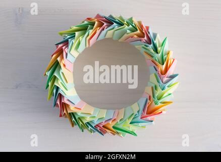Origami anello, astratto struttura circolare parametrica realizzata con fogli di carta colorati adagia su una scrivania bianca, vista dall'alto Foto Stock