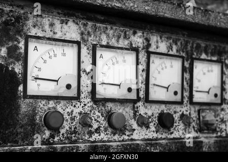 Amperometri quadrati industriali in fila montati in un vecchio pannello di controllo grungy, foto in bianco e nero da primo piano con messa a fuoco morbida selettiva Foto Stock