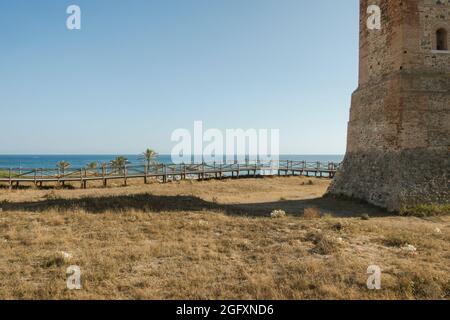 Passerella in legno nella vegetazione protetta delle dune con la torre di osservazione moresca, Torre dei ladri, sulla spiaggia di Cabopino vicino a Marbella, Andalusia, Spagna. Foto Stock