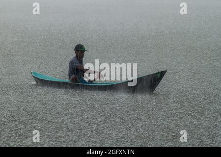 PORTOBELO, PANAMA - 28 MAGGIO 2016: Uomo locale nella sua canoa durante una pioggia pesante. Foto Stock