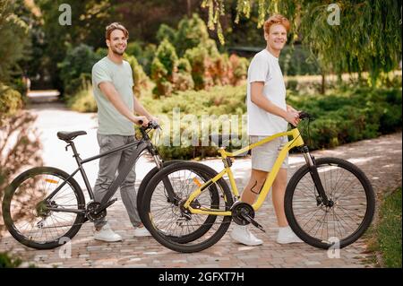 Due simpaticisti giovani con le loro biciclette che guardano avanti Foto Stock