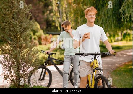 Due ciclisti in piedi all'aperto durante la pausa caffè Foto Stock