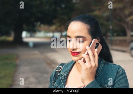 Giovane latino femmina che parla al telefono e sorride Foto Stock