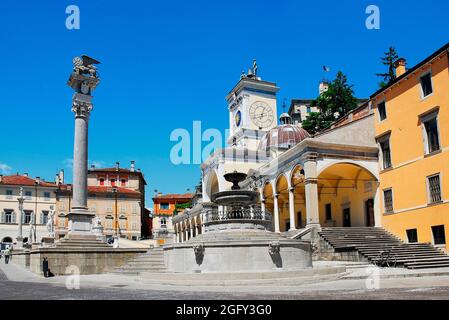 Piazza della Liberta a Udine, Italia nord-orientale. Sulla destra si trova la Loggia di San Giovanni del XVI secolo con una fontana in primo piano e una statua di leone Foto Stock