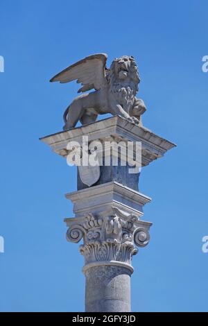 Una statua del leone di San Marco in cima a una colonna all'esterno della Loggia di San Giovanni in Udine, Italia in Piazza della Liberta, risalente al XVI secolo Foto Stock