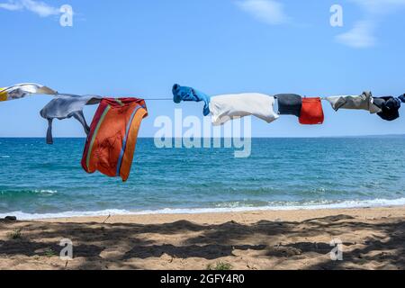Camper vestiti su una linea di lavaggio vicino al mare su una spiaggia nel sud della Grecia. Foto Stock