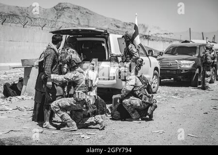 Le forze della coalizione finlandese assistono gli sfollati per il trattamento successivo durante un'evacuazione all'aeroporto internazionale Hamid Karzai, Kabul, Afghanistan, 24 agosto. I membri del servizio degli Stati Uniti e le forze di coalizione stanno assistendo il Dipartimento di Stato con un'operazione di evacuazione non combattente (NEO) in Afghanistan. (STATI UNITI Foto del corpo marino di staff Sgt. Victor Mancilla) Foto Stock